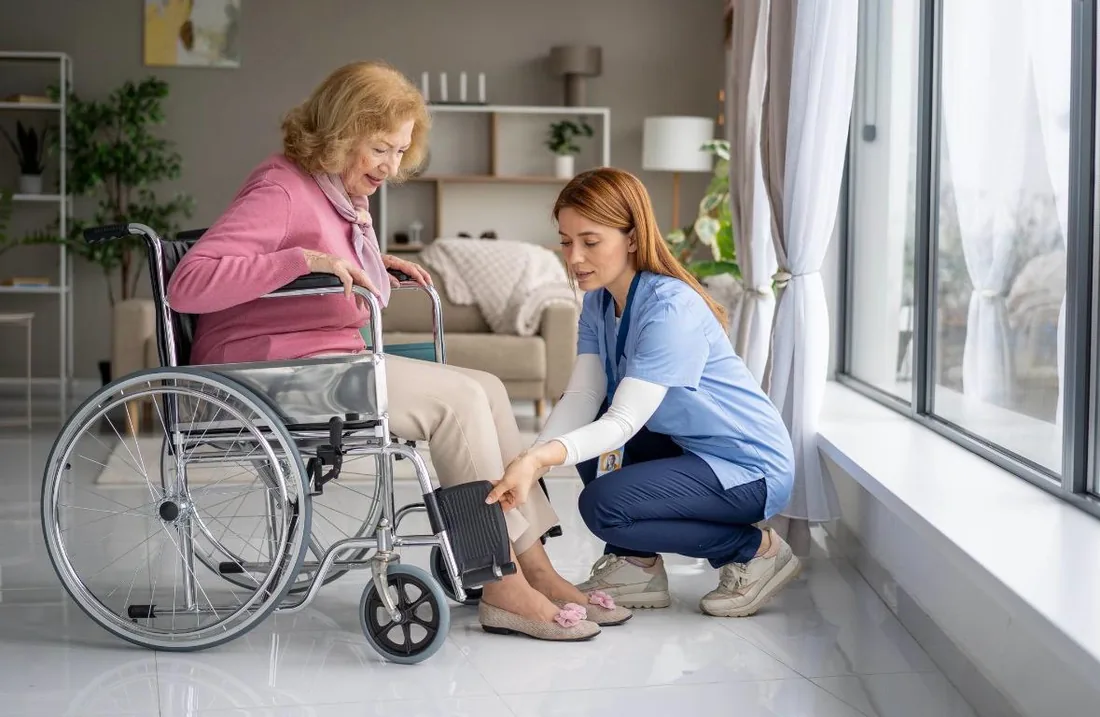 Caregiver providing mobility assistance to an older adult in a wheelchair
